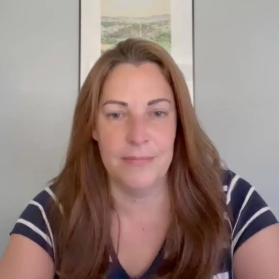 a woman with long hair sitting in front of a painting