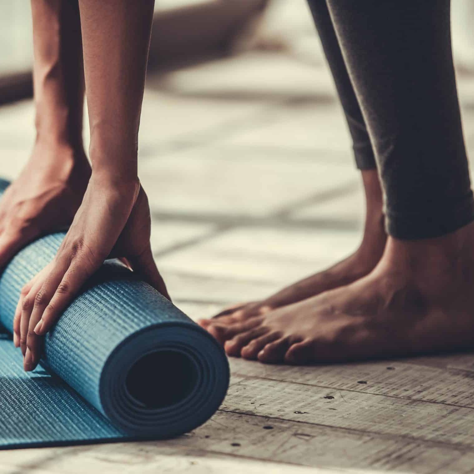Cropped,Image,Of,Afro,American,Rolling,Yoga,Mat a person rolling a yoga mat